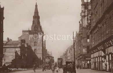 Vintage black and white photograph of a city street with tall buildings and a clock tower 