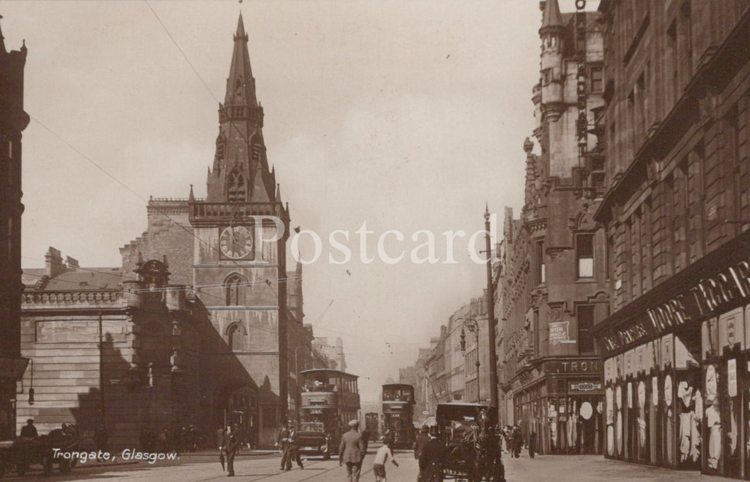 Vintage black and white photograph of a city street with tall buildings and a clock tower 