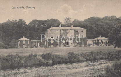 Vintage black and white postcard of a large house with trees and grass in the foreground.