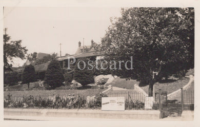 Vintage black and white postcard of a residential area with houses and trees.