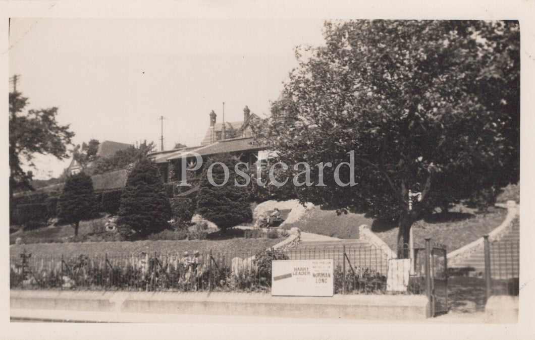 Vintage black and white postcard of a residential area with houses and trees.
