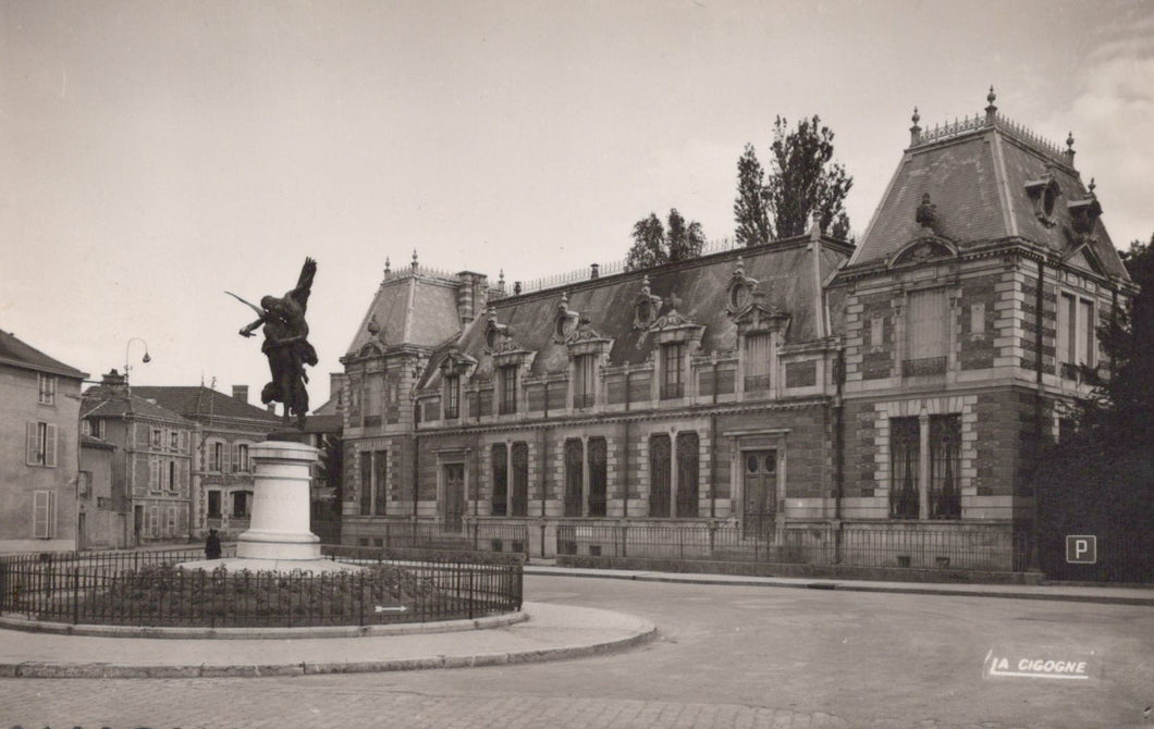 Historical black and white photo of a building with a statue in front