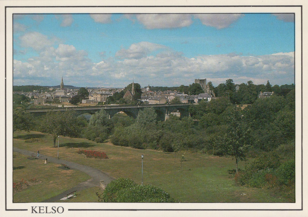 View of Kelso with a bridge and buildings under a blue sky with clouds.