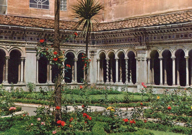 Cloister with columns and a garden with flowers in front of a building