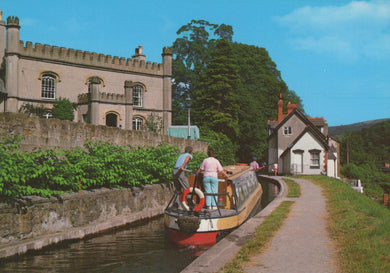 Barge on a canal with a castle-like building and trees in the background