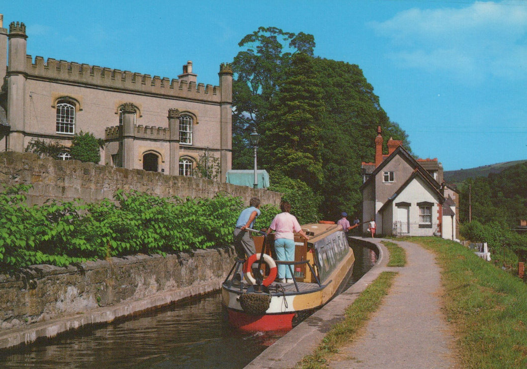Barge on a canal with a castle-like building and trees in the background