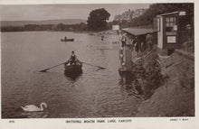 Load image into Gallery viewer, Vintage black and white photograph of a person rowing a boat on Roath Park Lake with a swan nearby.
