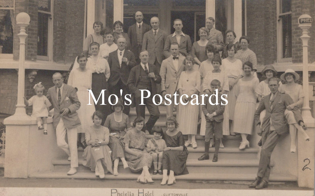 Vintage black and white photo of a family gathering on a porch with 'Mo's Postcards' text overlay.