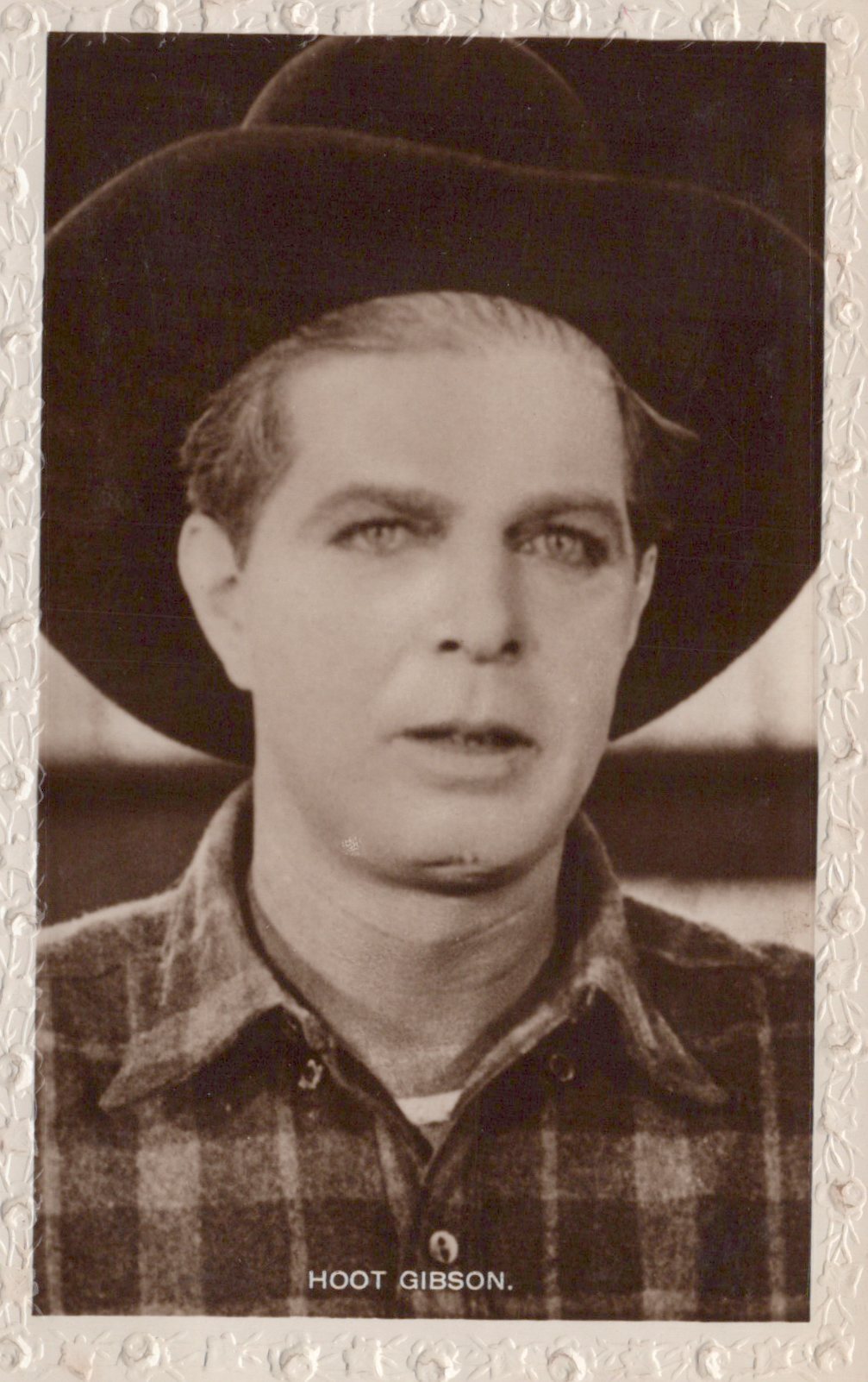 Vintage black and white photo of a man wearing a hat and plaid shirt with 'Hoot Gibson' text.