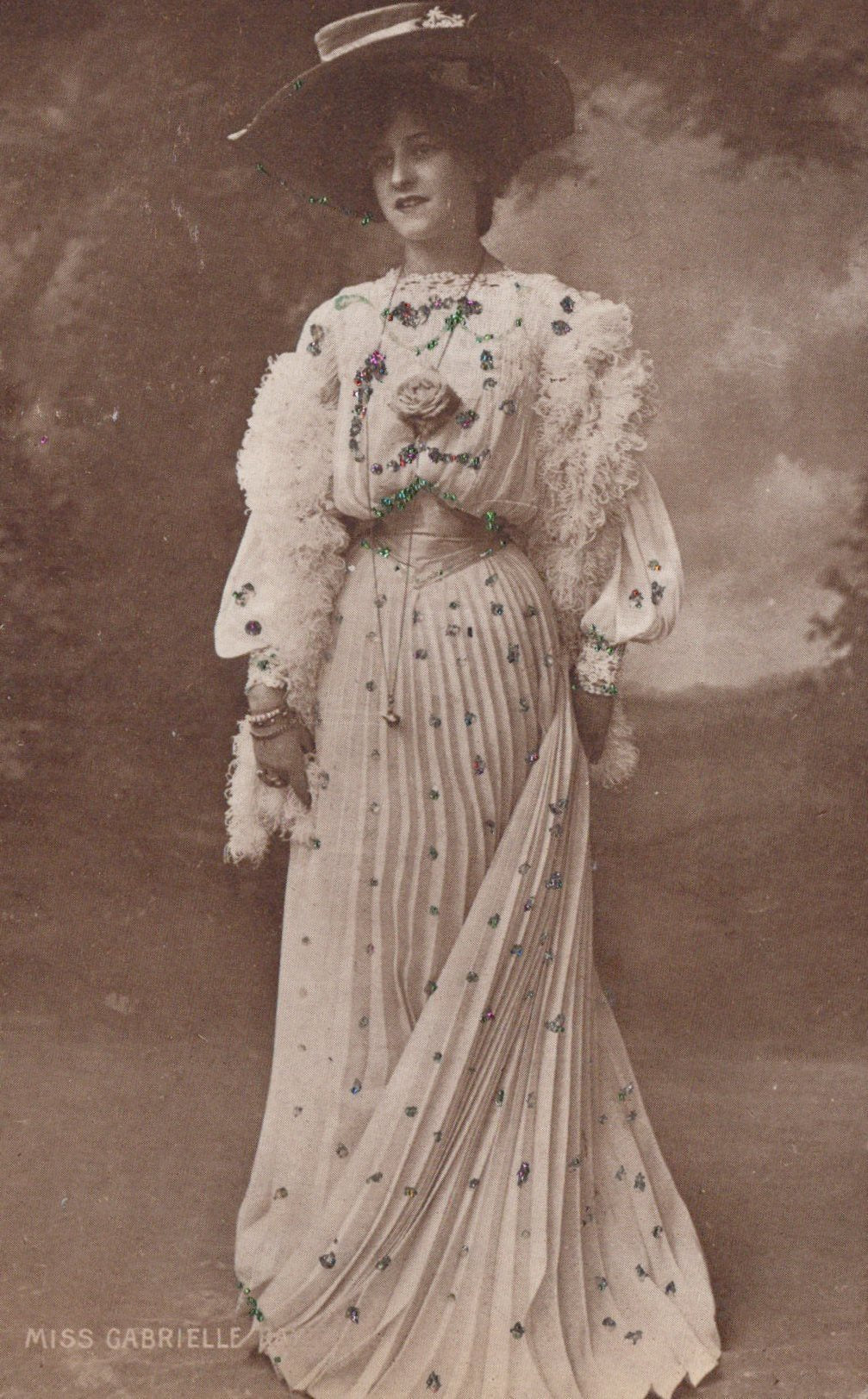 Vintage photograph of a woman in an elaborate dress with floral details against a cloudy sky.