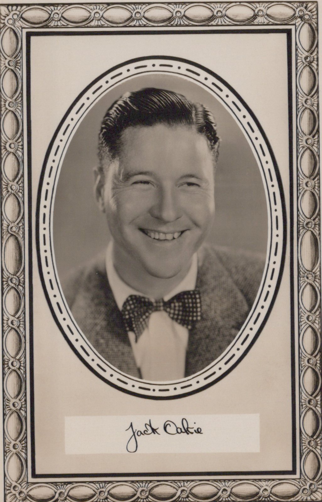 Vintage black and white portrait of a man with a bow tie in an ornate frame.