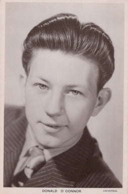 Vintage black and white portrait of a man with styled hair, wearing a suit.