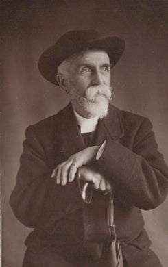 Black and white portrait of a man wearing a hat and coat, holding an umbrella.
