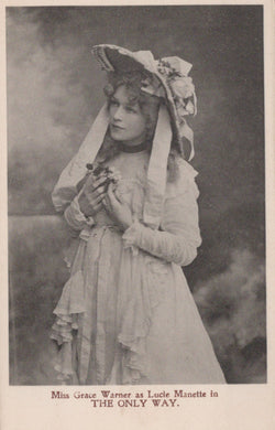 Vintage photograph of a woman in an elaborate dress and hat, holding a flower, with text at the bottom.
