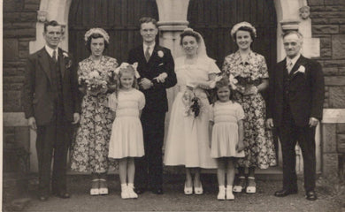Black and white photograph of a wedding party in front of a building