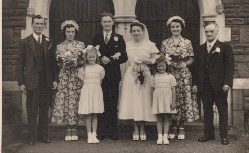 Black and white photograph of a wedding party in front of a building