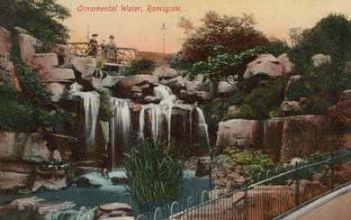 Vintage-style image of a decorative water feature with rocks and people in the background.