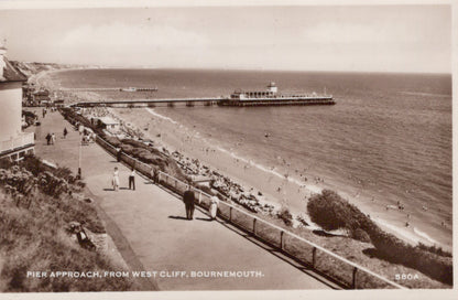 Vintage black and white photo of a beach scene with a pier and promenade.