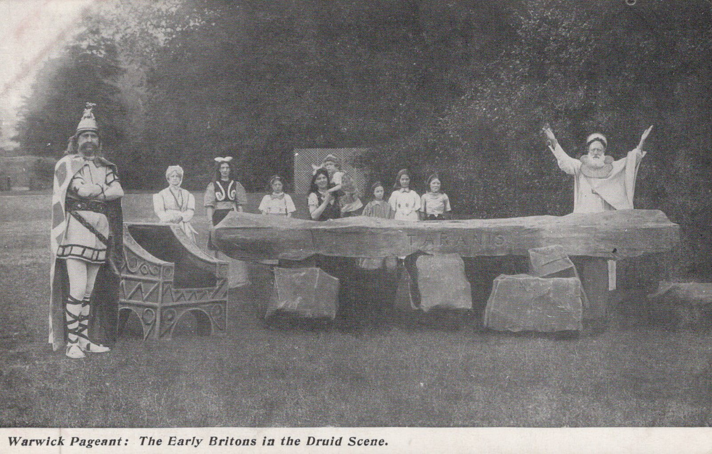 Historical performance scene with people in costumes around a stone circle.