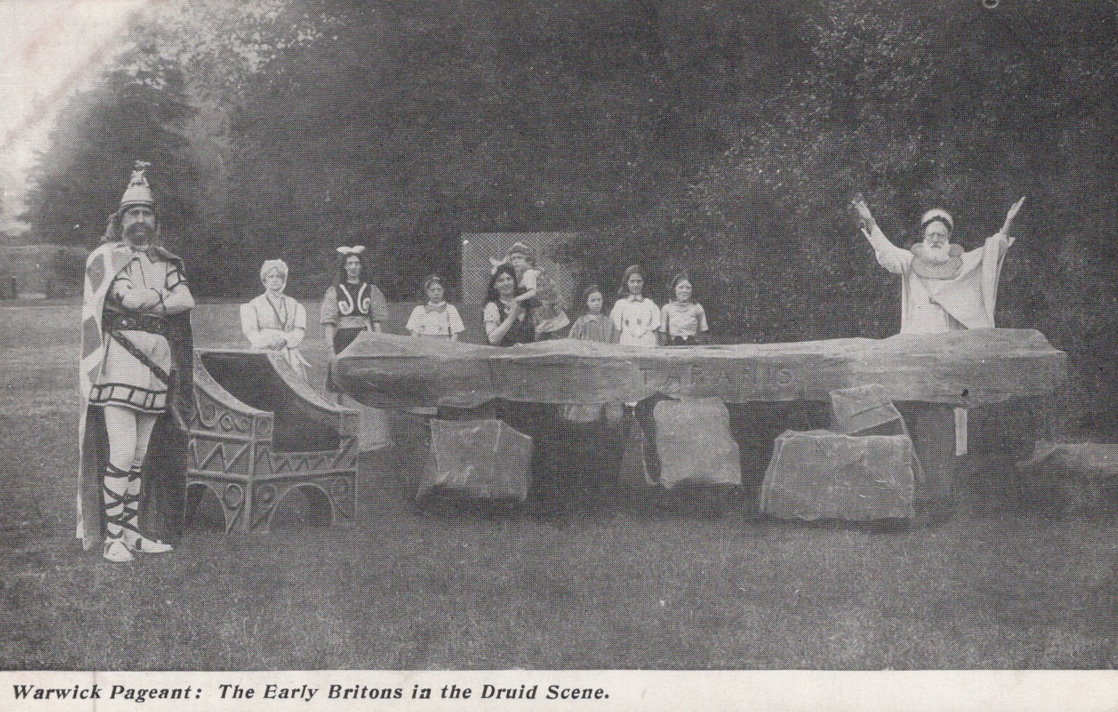 Historical performance scene with people in costumes around a stone circle.