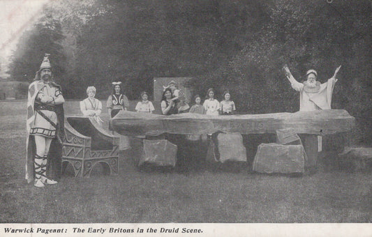 Historical performance scene with people in costumes around a stone circle.