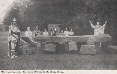 Historical performance scene with people in costumes around a stone circle.