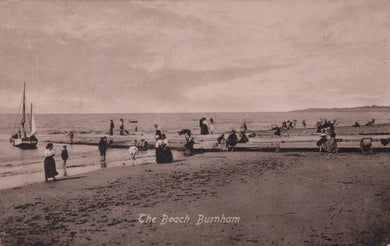 Vintage black and white postcard of a beach scene with people and boats.