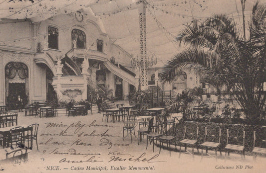 Vintage interior of a large building with palm trees and tables, likely a casino or similar venue.