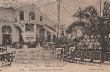 Load image into Gallery viewer, Vintage interior of a large building with palm trees and tables, likely a casino or similar venue.
