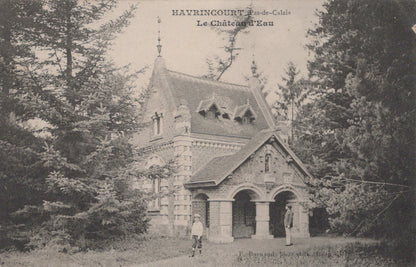 Vintage black and white photo of a stone building with a pointed roof, surrounded by trees.
