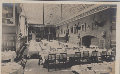 Vintage black and white photo of a dining hall interior with tables, chairs, and decorative elements.