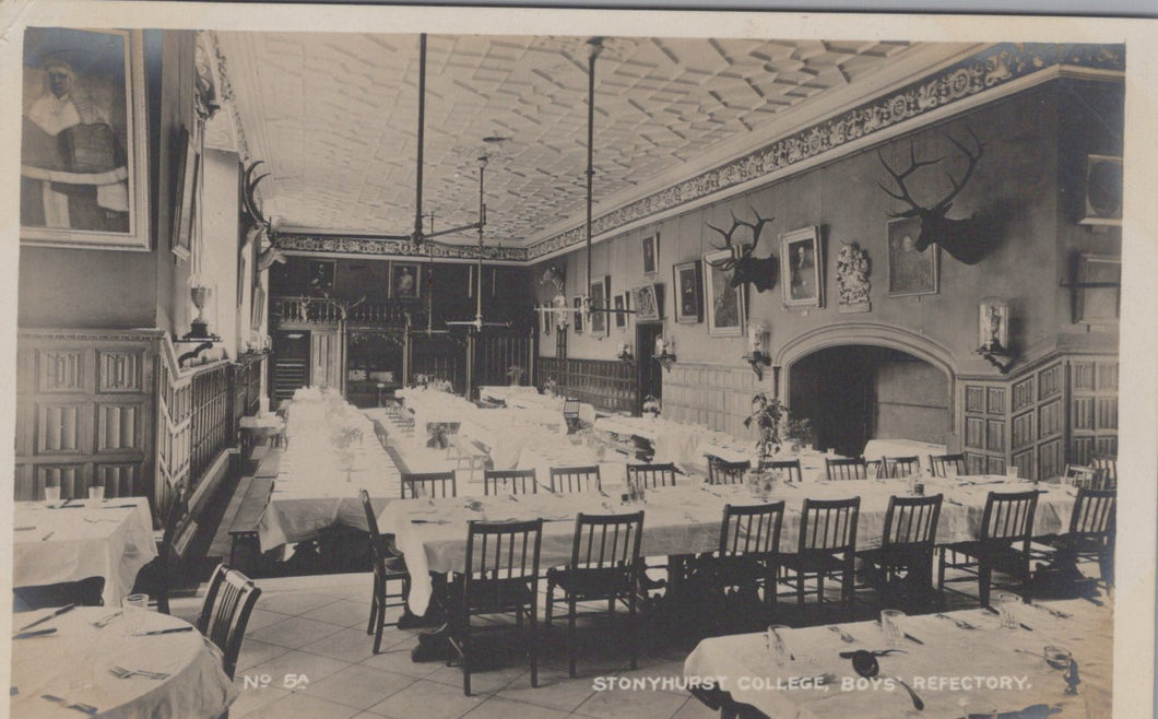 Vintage black and white photo of a dining hall interior with tables, chairs, and decorative elements.