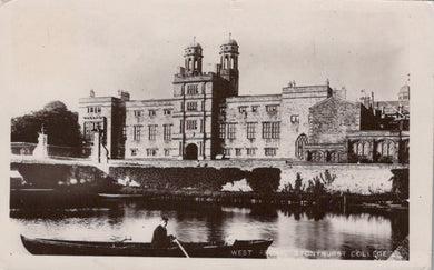 Historic black and white photo of a large building with a river and boat in front