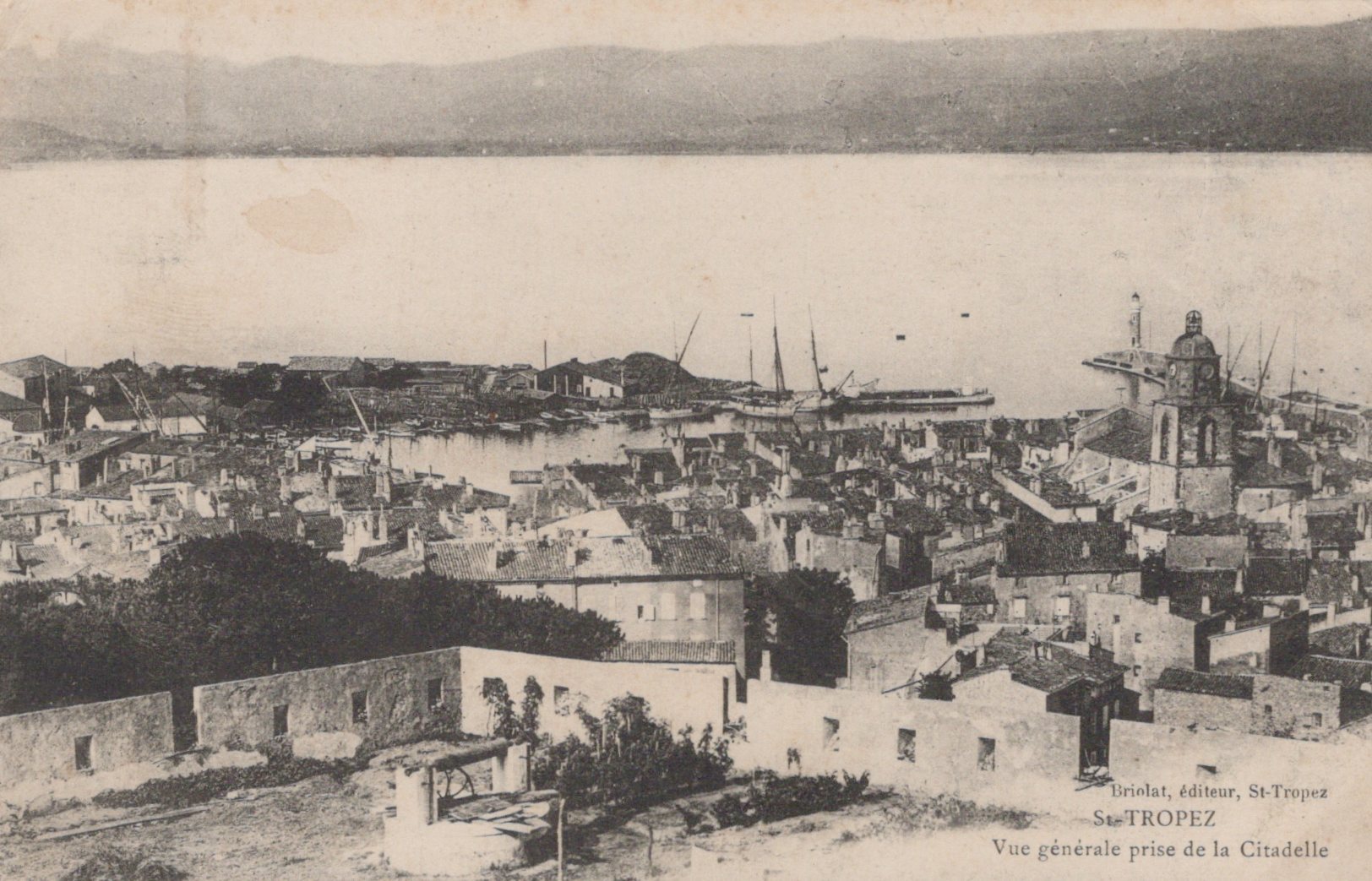 Vintage black and white photo of a coastal town with buildings and a harbor.