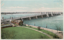 Load image into Gallery viewer, Vintage colorized photograph of a bridge over a body of water with green grass and a path in the foreground.
