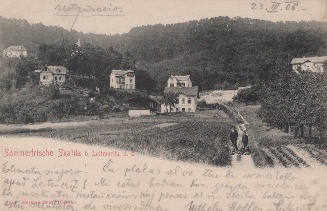 Vintage black and white photo of a village with houses and people on a path, dated 23. V. 06.