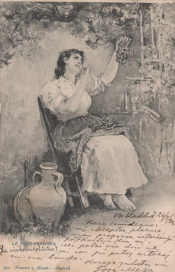 Woman sitting in a chair with a basket of grapes, surrounded by trees and a vase.