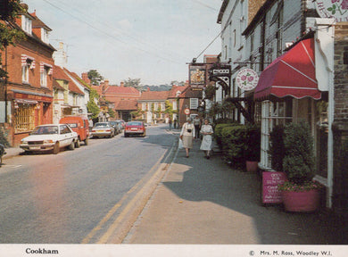 Vintage street scene in a small town with shops and cars.