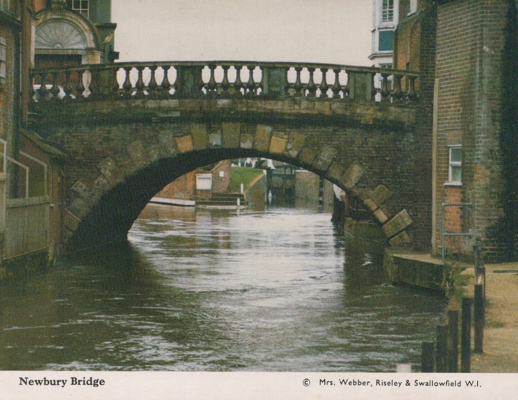 Bridge over a canal with buildings on either side, featuring a watermill.