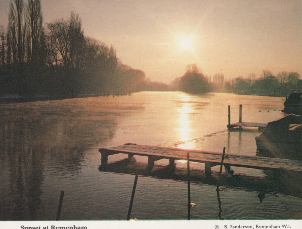 Sunset over a lake with a dock and trees in the background