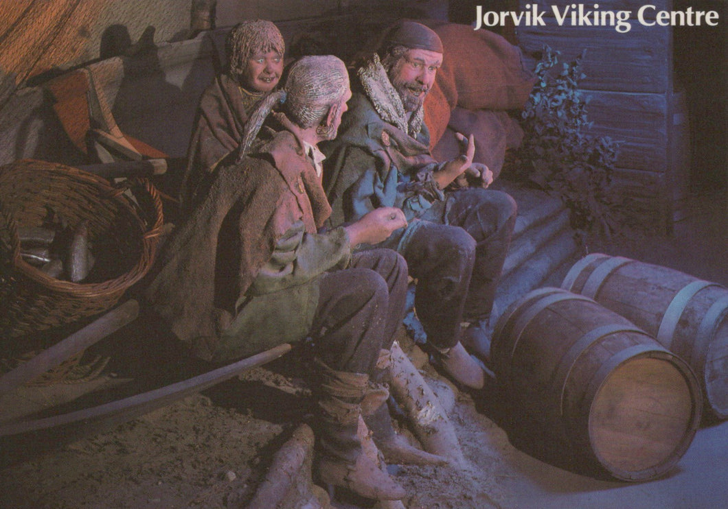 Illustration of three Vikings sitting around a fire with barrels and Viking gear in the background, labeled 'Jorvik Viking Centre'.