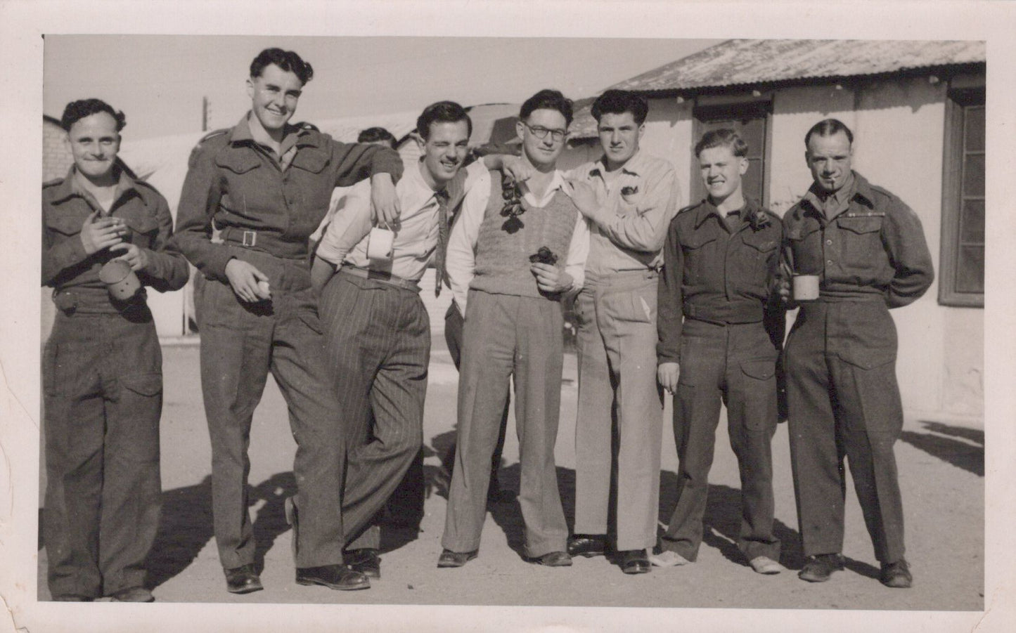 Black and white photo of six men in military uniforms standing together outdoors.