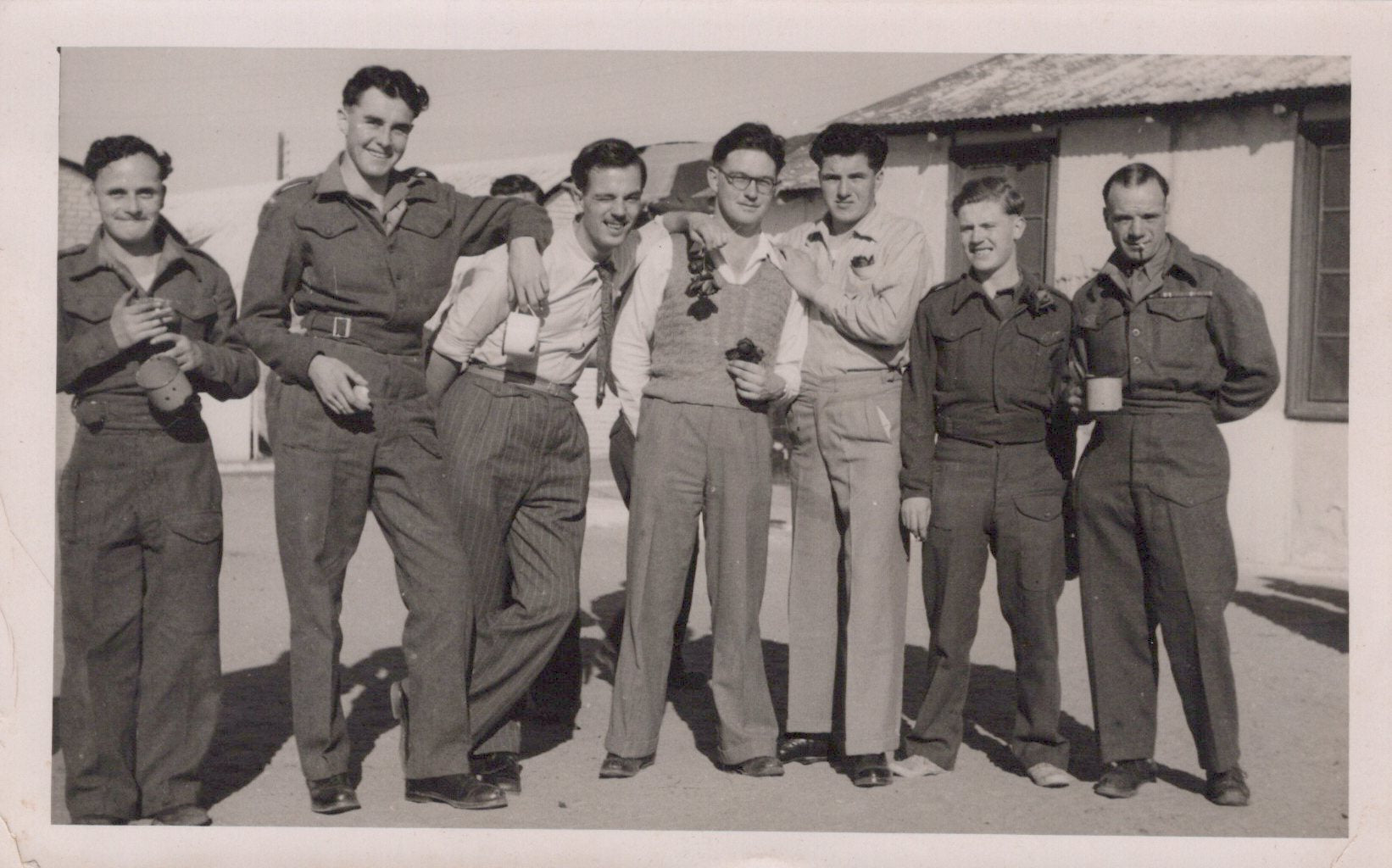Black and white photo of six men in military uniforms standing together outdoors.