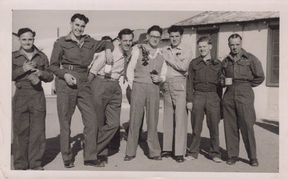 Black and white photo of six men in military uniforms standing together outdoors.