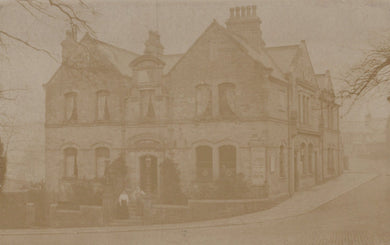 Vintage sepia-toned photograph of a large house with a prominent chimney.