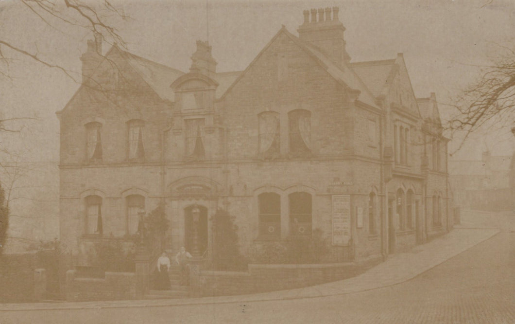 Vintage sepia-toned photograph of a large house with a prominent chimney.