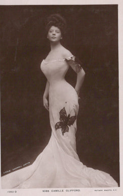 Vintage photograph of a woman in an elegant gown with a butterfly design, against a dark background.