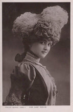 Load image into Gallery viewer, Vintage black and white portrait of a woman wearing an elaborate hat with feathers and flowers.
