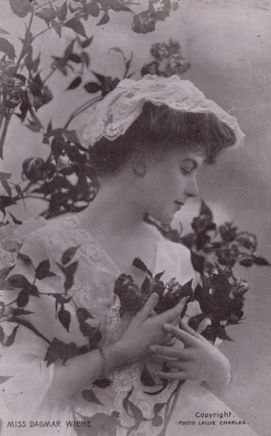 Vintage photograph of a woman holding flowers with a decorative hat.
