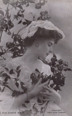Vintage photograph of a woman holding flowers with a decorative hat.